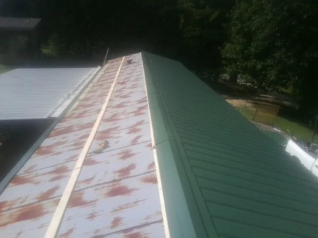 Old rusted panels beside newly installed green metal roofing — Wind Damage Roof Repair by Roofing Brothers in Lyon Station