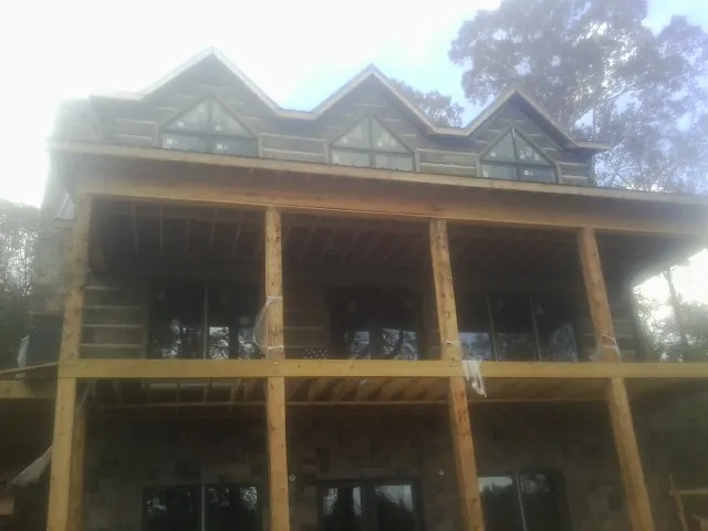 Dormers and porch framing on a large log home under construction — Roof Coating work by our crew in Lyon Station
