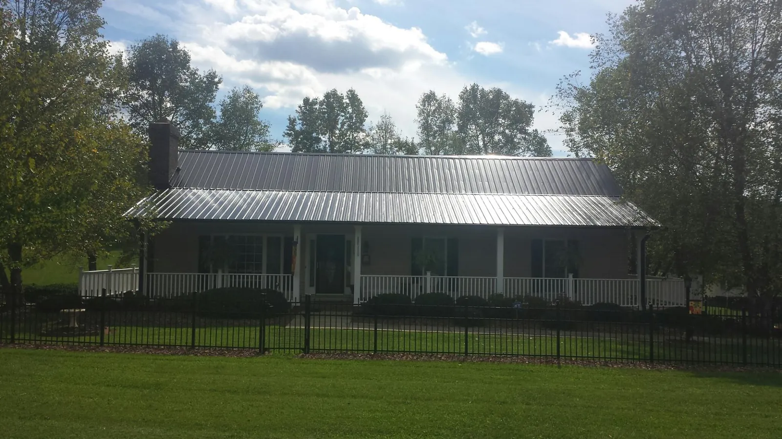 Gray metal roof on a brick ranch with a full width front porch — Gutter Guard Installation work by our crew in Lyon Station