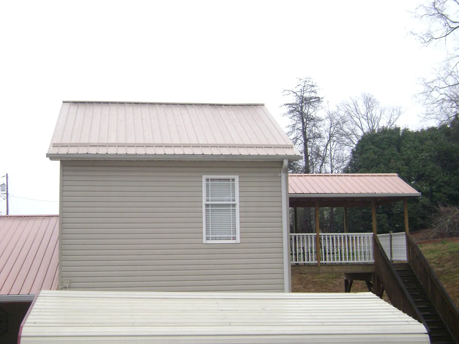 Tan metal roofs on a two story addition and attached porch, from a Roof Replacement job in Lyon Station