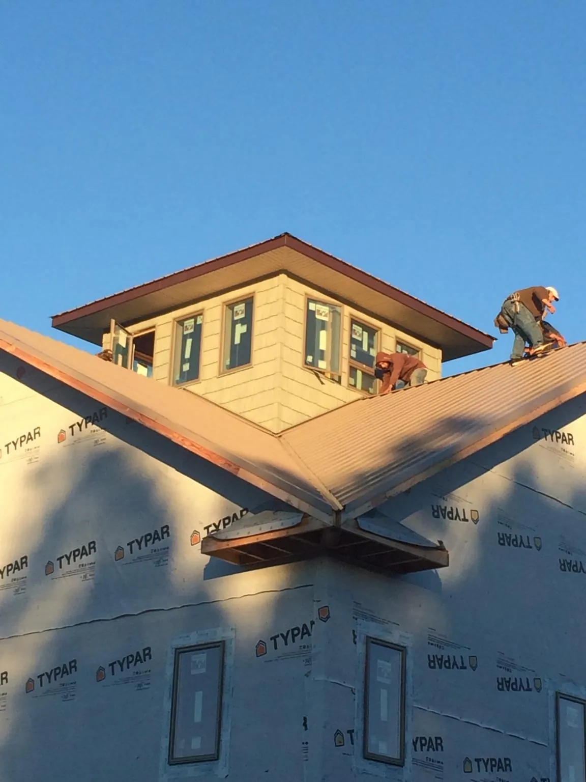Roofers working around a rooftop cupola on a new metal roof at sunset — Roof Waterproofing in Lyon Station by Roofing Brothers
